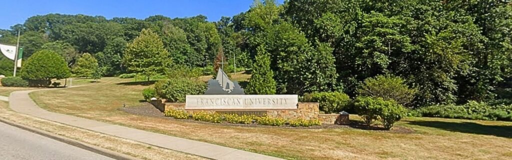 Franciscan University of Steubenville campus entrance sign near student housing options.
